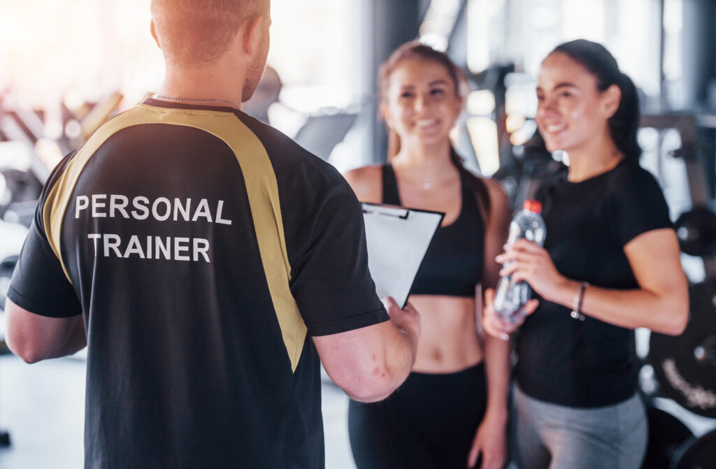 two young girls in sportive clothes is in the gym together at daytime with their male personal trainer two young girls in sportive clothes is in the gym together at daytime with their male personal trainer